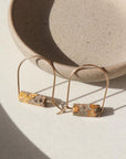 14k gold fill Leopard Skin Jasper Arches placed against a gray plate in the sunlight.