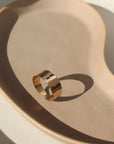 14k gold fill Luxe Ring placed on a tan plate in the sunlight. This ring features Lightly hammered and sophisticated ring cuff.