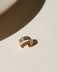 A 14k gold fill double layered ear cuff, displayed on a cream back drop in the sunlight