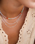 Close-up of a sterling silver necklace stack paired with a vibrant beaded necklace for a pop of color
