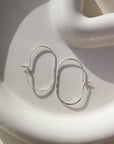 925 sterling silver capsule hoops laid on a white plate. Handmade in Eau Claire, Wisconsin.