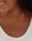 Model wearing Agave Necklace with a faceted sage green turquoise teardrop pendant on a reflective gold filled box chain, designed for everyday wear and layering.