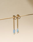 A 14k gold fill back drop with a dainty curb chain, with three opal gemstones and one mini pearl set at the bottom