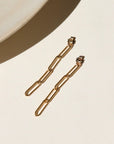 14k gold fill thick paper clip chain backdrops, displayed on a cream backdrop in the sunlight.