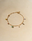 14k gold fill gemstone charm anklet with a link chain laying on a beige dish in natural light