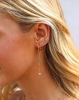 Model wearing 14k gold filled drop earrings with colorful opals in between links.