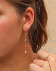 Model wearing Disco Opal Earrings featuring six multicolored opals on a bar, dot, and dash chain design in gold fill.