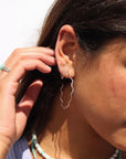 Model wearing a sterling silver hoop with wave-like textured wire, model paired it with a huggie with the same textured pattern