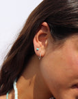 Model wearing a wave like sterling silver textured huggie earring. She pairs her hoop with a 4mm sterling silver turquoise stud.