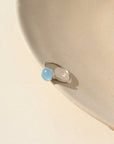 A sterling silver hammered gold band with a 8mm aquamarine gemstone set in a silver bezel.