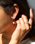 A post earring with 14k gold fill wire earring with a 8mm moonstone gemstone. The earrings are worn by a model, who is also wearing other 14k gold fill and moonstone jewelry. Her hand is up tucking her hair behind her ear.