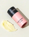 Pink lip balm with black cap on a light beige background