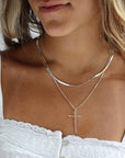 Model is wearing a sterling silver thin bar and link chain featuring a 1 1/2" hammered cross pendant.