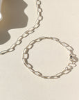 Silver chain necklace and bracelet on a beige background