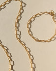 Gold chain necklace and bracelet on a beige background