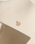 14k gold fill round disc with marathon miles hand stamped on it on a light dish