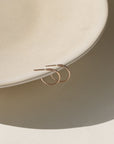 Gold hoop earrings on a light beige plate with a neutral background