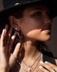 Model wearing Sterling silver cross stud earrings. Along with other sterling silver jewelry. Model is wearing a black denim top with a black hat.