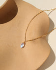 A 14k gold fill box chain featuring a Marquise Moonstone Gemstone wired wrapped at the end. Necklace is displayed on a orange dish.
