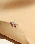 A 3mm pink tourmaline gemstone set into a sterling silver stud, displayed in the sunlight.