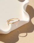 14k gold fill skinny ring laid on wavy plate in sunlight