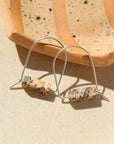 Sterling Silver Leopard Skin Jasper Arch Earrings by Token Jewelry laying next to a speckled ceramic plate