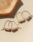 Sterling Silver and 14k gold fill Leopard Skin Jasper Arch Earrings by Token Jewelry laying next to a speckled ceramic plate