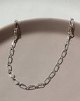 925 Sterling silver Brooklyn Anklet laid on a tan plate in the sunlight.