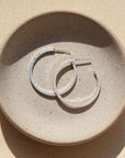 petite maeve hoops in 925 sterling silver by token jewelry, a medium-sized hoop with a post, featuring a textured edge