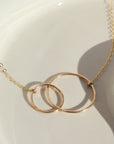 14k gold fill Unity Necklace laid on a white plate in the sunlight.