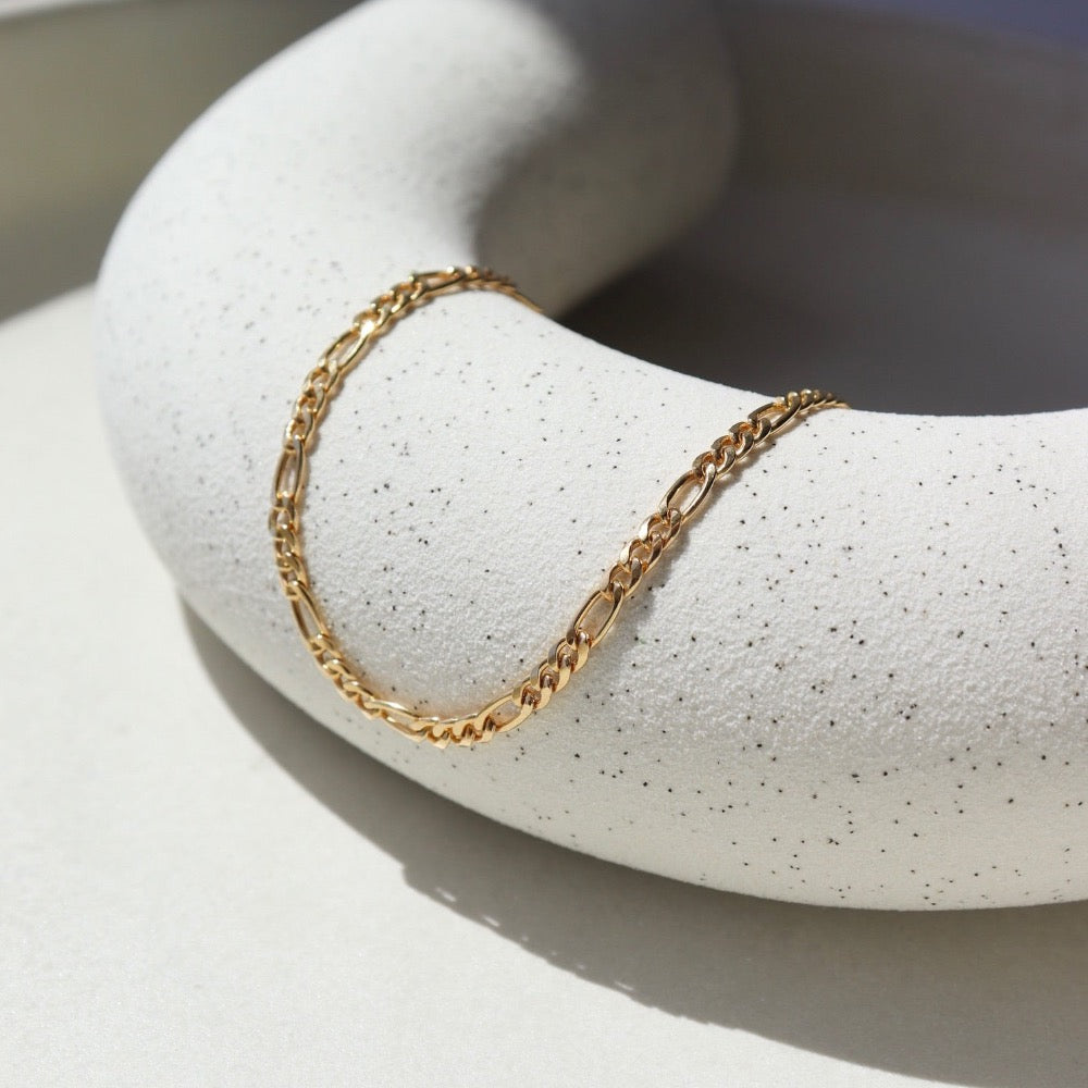 14k Gold Fill Gigi Necklace laid on a white plate in the sunlight.