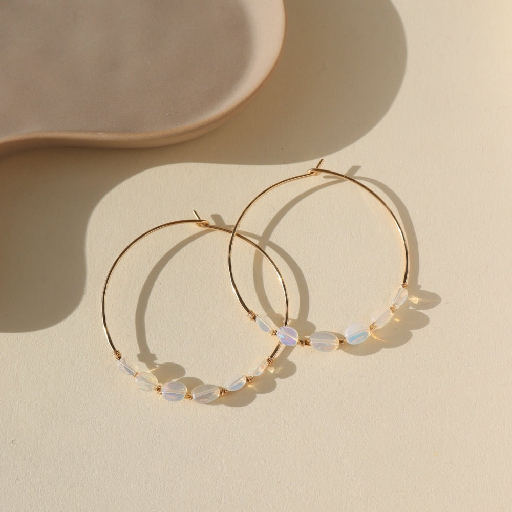 14k gold fill or sterling silver hoops, handmade and lightly hammered for shine, then adorned with six genuine australian opals that are delicately wire-wrapped. Handmade by Token Jewelry in Eau Claire, WI