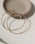 14k gold fill Soleil Hoops laid on a white paper in the sunlight