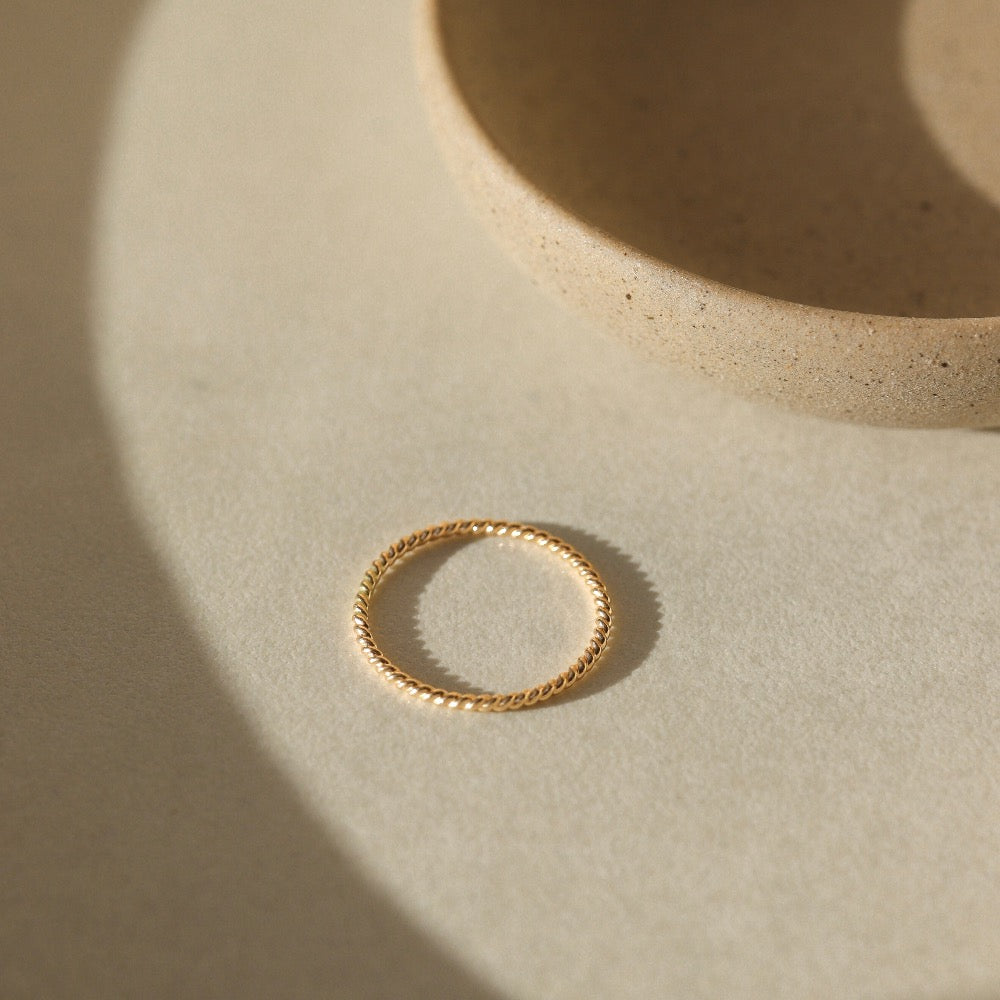 Simple spiral gold band, displayed on a white dish. 