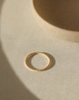 Simple spiral gold band, displayed on a white dish. 