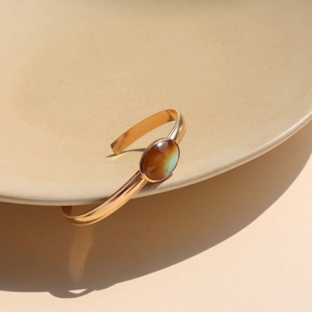 A 14k gold fill smooth cuff with a 13x18mm turquoise stone set at its center