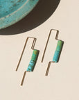 14k gold fill threaders with two turquoise tube shaped gemstones, the earrings are displayed on a cream backdrop 