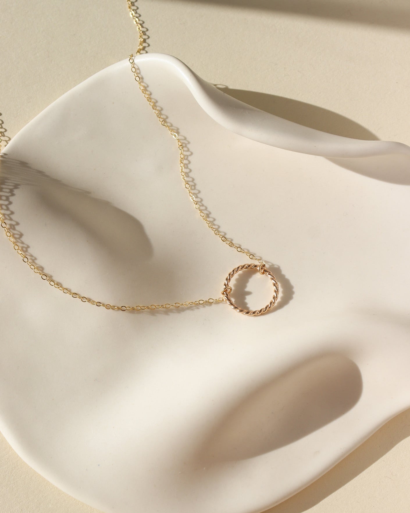 14k gold fill spiral necklace by token jewelry, photographed on a white dish