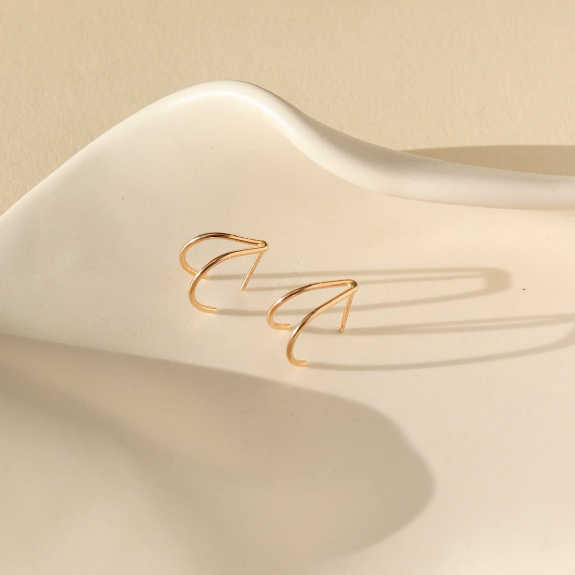 14k gold fill wishbone studs laid on a white plate