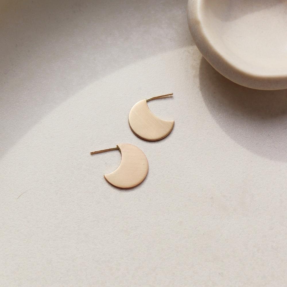 14k gold filled Mini echo studs laid on a gray plate in the sunlight.