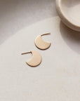 14k gold filled Mini echo studs laid on a gray plate in the sunlight.