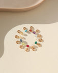 tiny birthstone gems photographed in a circle on a sunlit tabletop