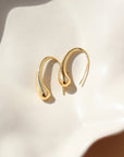 14k gold fill golden drop earrings laid on a white plate.