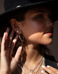 34mm classic sterling silver hoop earring photographed on a brunette model wearing a black cowboy hat and other silver jewelry made by Token Jewelry