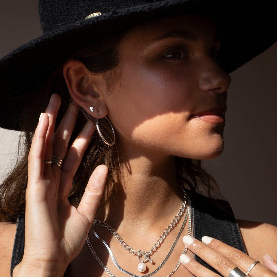Model wearing a 925 Sterling silver cross stud earrings. Along with other sterling silver jewelry.