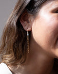 gold chain earrings featuring a small pearl on a hook-style earring, photographed on a model