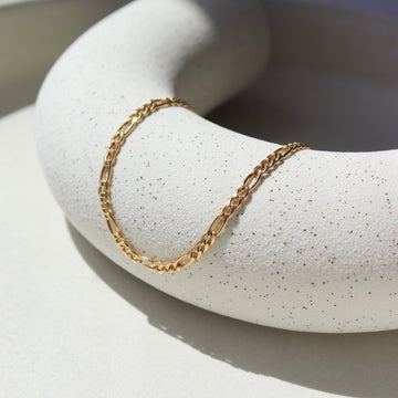 14k Gold Fill Gigi Necklace laid on a white plate in the sunlight.