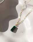 14k gold fill Malachite Necklace laid on a white plate in the sunlight. This necklace features the cossette chain with the Malachite gemstone.