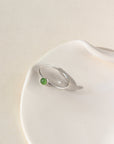 4mm Jade Gemstone Ring set in a Sterling Silver bezel with simple hammered ring band. The Ring is sitting on a white ceramic plate.