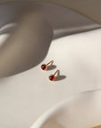 4mm Red Garnet Stud Earrings with 14k gold fill post and bezel, photographed on a curvy white ceramic dish